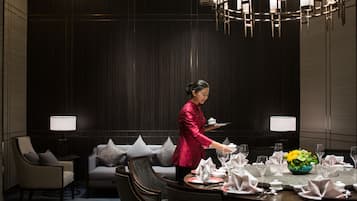 A well-appointed dining area with a round table set for a meal, a sofa with cushions, and a modern chandelier.