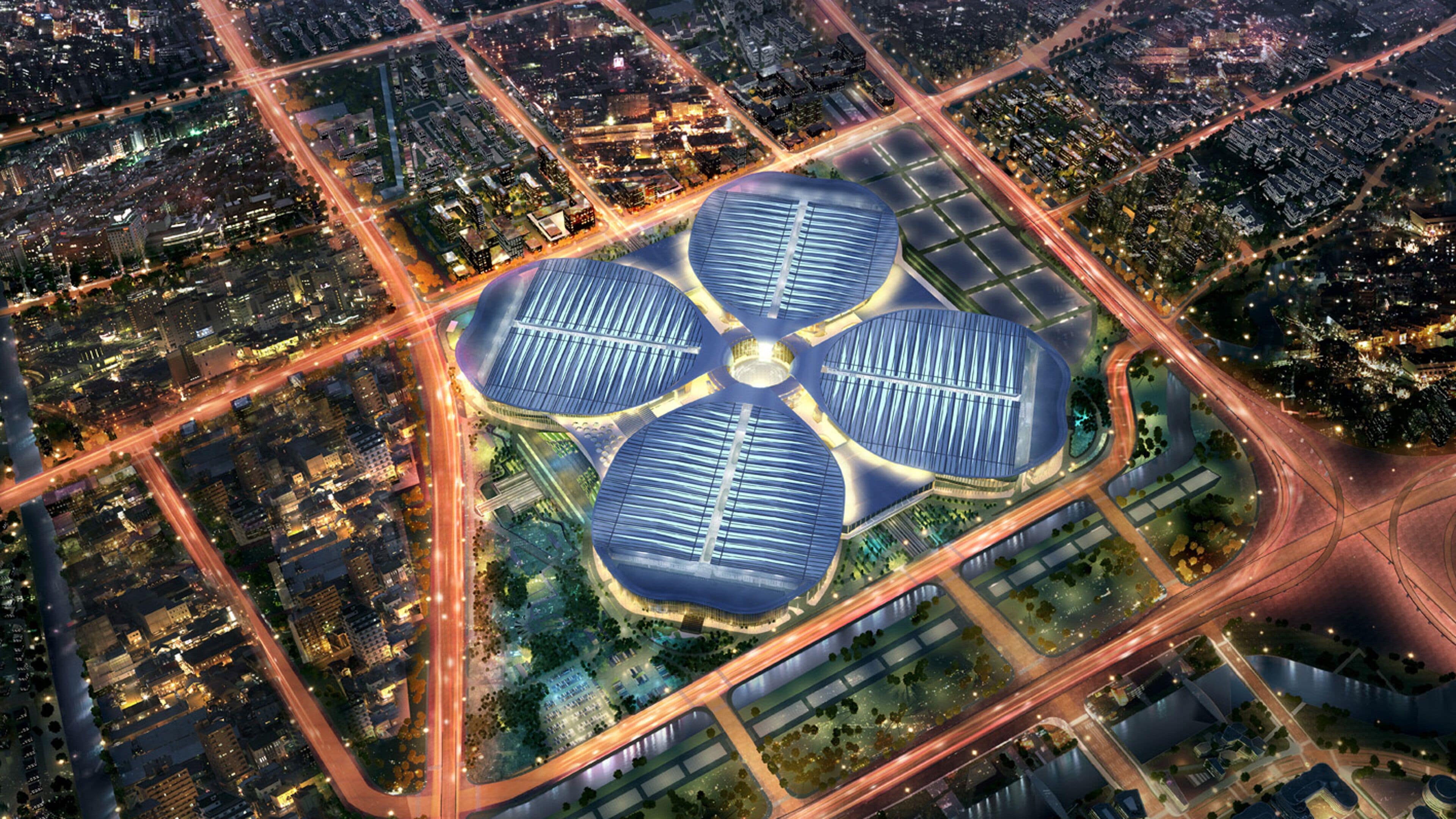 A modern building with a unique circular design, surrounded by a well-planned urban area with roads and greenery.
