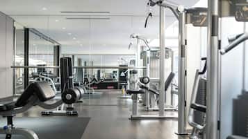 Een moderne sportschool met diverse fitnessapparaten, glazen wanden en een schoon, goed verlicht interieur.