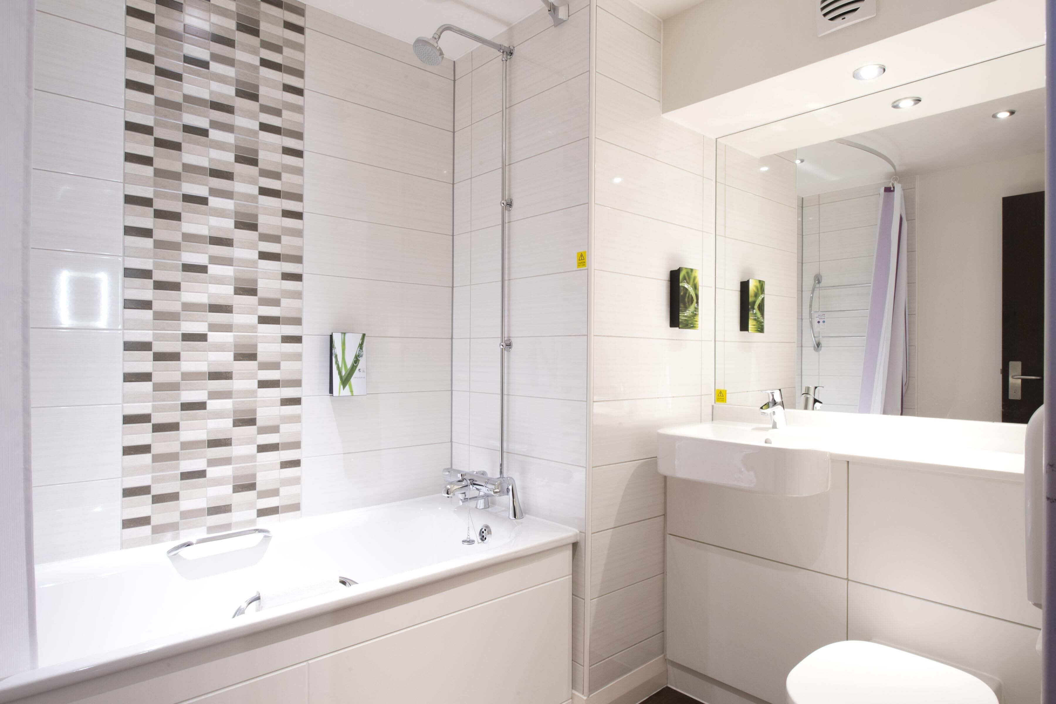 Et moderne badeværelse med et stort badekar, bruser og toilet.