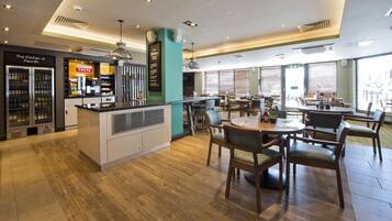 A modern restaurant with a central island, seating area, and a kitchen counter.