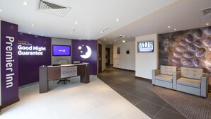 Een hotel receptie met een incheckbalie, een receptiebalie, een wandtelevisie en een muurschildering van eieren.