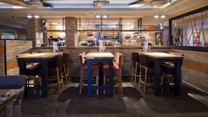 Een restaurant met houten tafels en stoelen, een bar en een bakstenen muur.