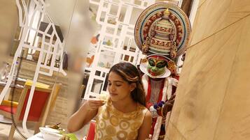 Un comedor con una mesa preparada para una comida, un muro decorativo y una persona sentada.