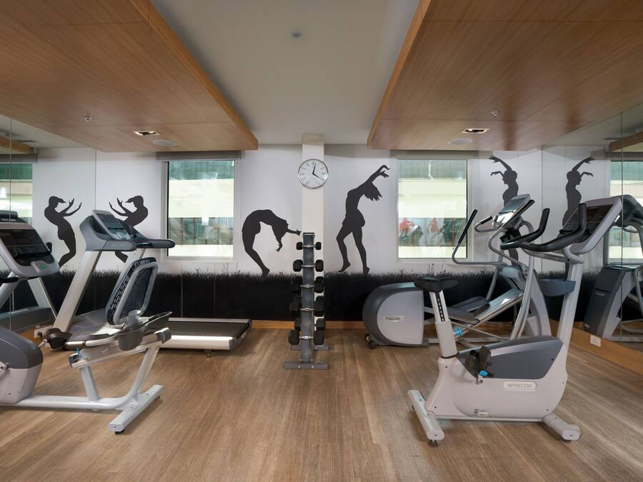 A gym with treadmills, elliptical machines, and a weight rack.