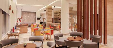 A modern hotel lobby with a central seating area, a reception desk, and a decorative wall with vertical wooden slats.