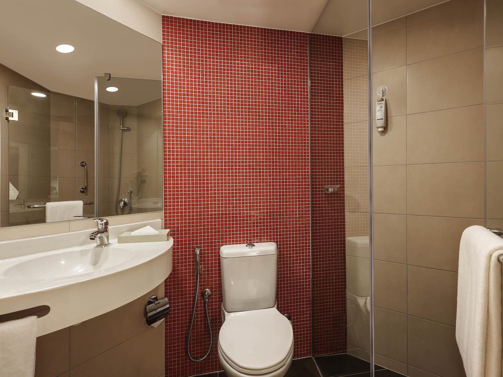 Une salle de bain avec un lavabo blanc, des toilettes et un espace douche.