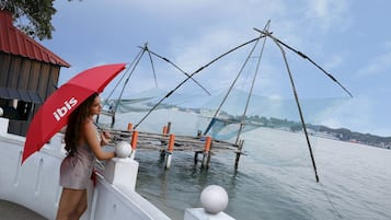 Una persona está junto al agua, con redes de pesca y un paraguas rojo.