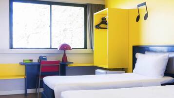 Una camera d'albergo con due letti, una scrivania con una sedia, una lampada e un armadio.