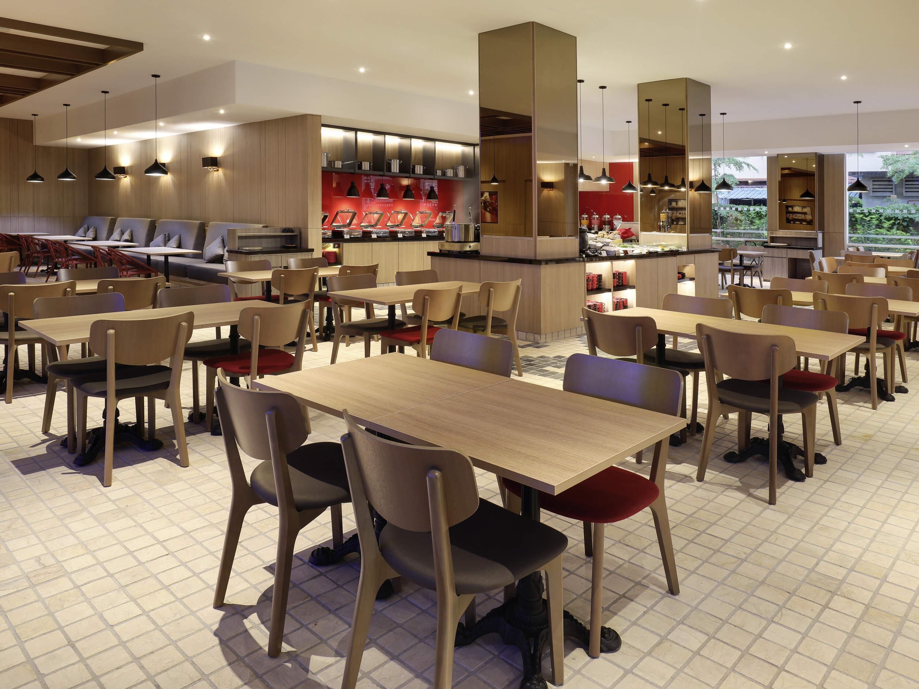 Un restaurante moderno con varias zonas de estar, incluyendo mesas y sillas, y una barra central.