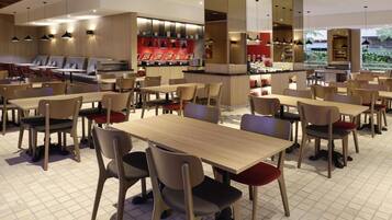 Un restaurante moderno con varias zonas de estar, incluyendo mesas y sillas, y una barra central.