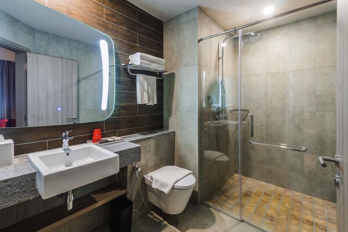 A modern bathroom with a glass-enclosed shower, a sink, and a toilet.