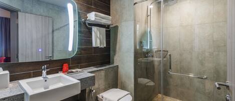 A modern bathroom with a glass-enclosed shower, a sink, and a toilet.