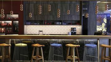 Zona de bar con taburetes de madera, encimera de mármol e iluminación colgante esférica.