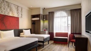 A hotel room with two beds, a desk, a chair, a TV, and a large window with curtains. - ibis Melaka (Malacca City)