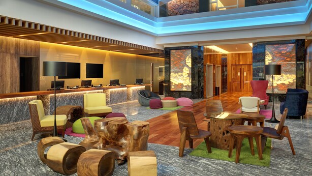 A spacious lobby with a reception desk, multiple seating areas, and a high ceiling with integrated lighting. - ibis Melaka (Malacca City)