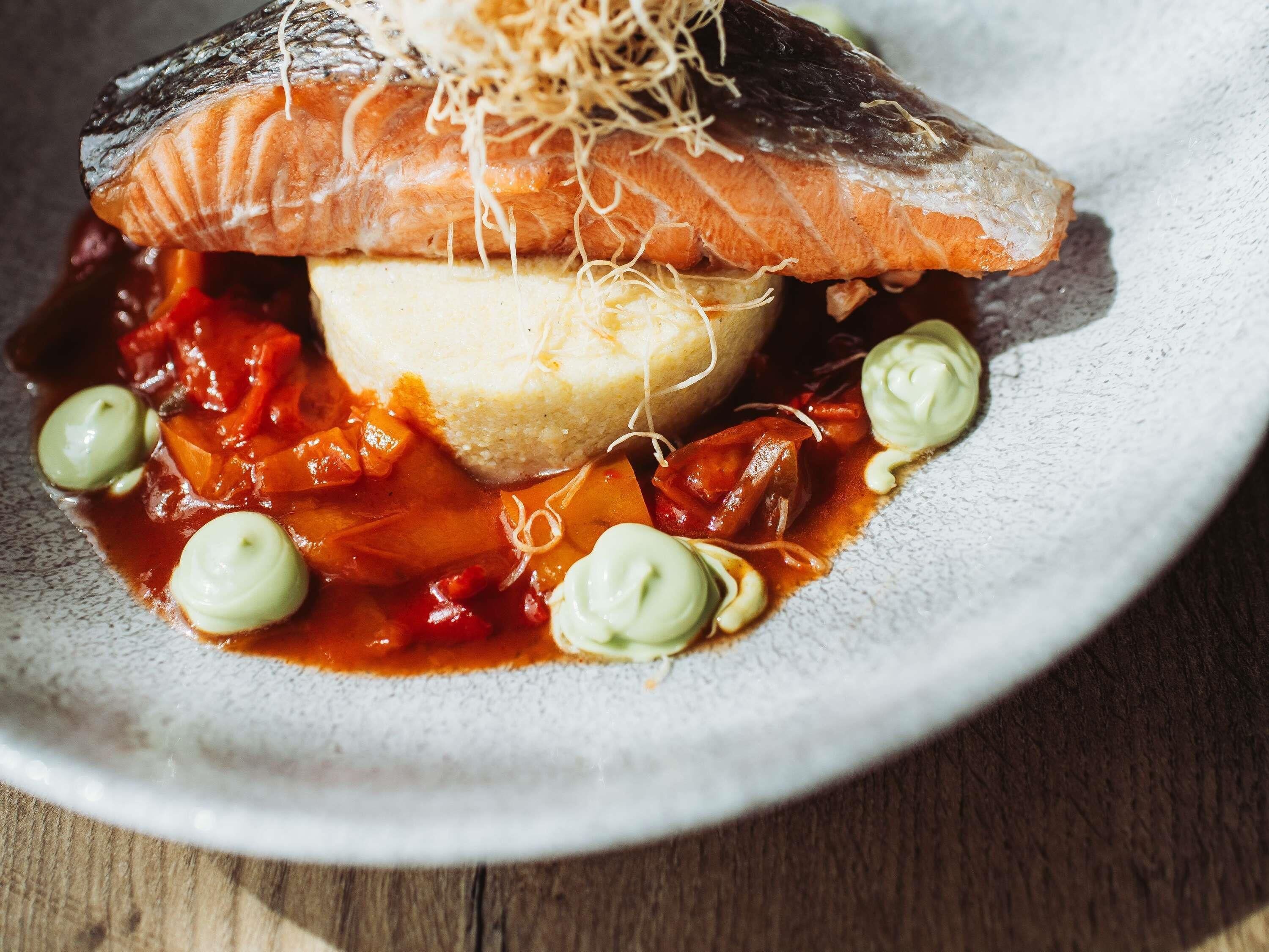 A plate with a fish, vegetables, and a mound of rice.