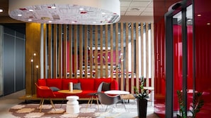Un interior moderno con un sofá rojo, mesas redondas y un separador de listones de madera.