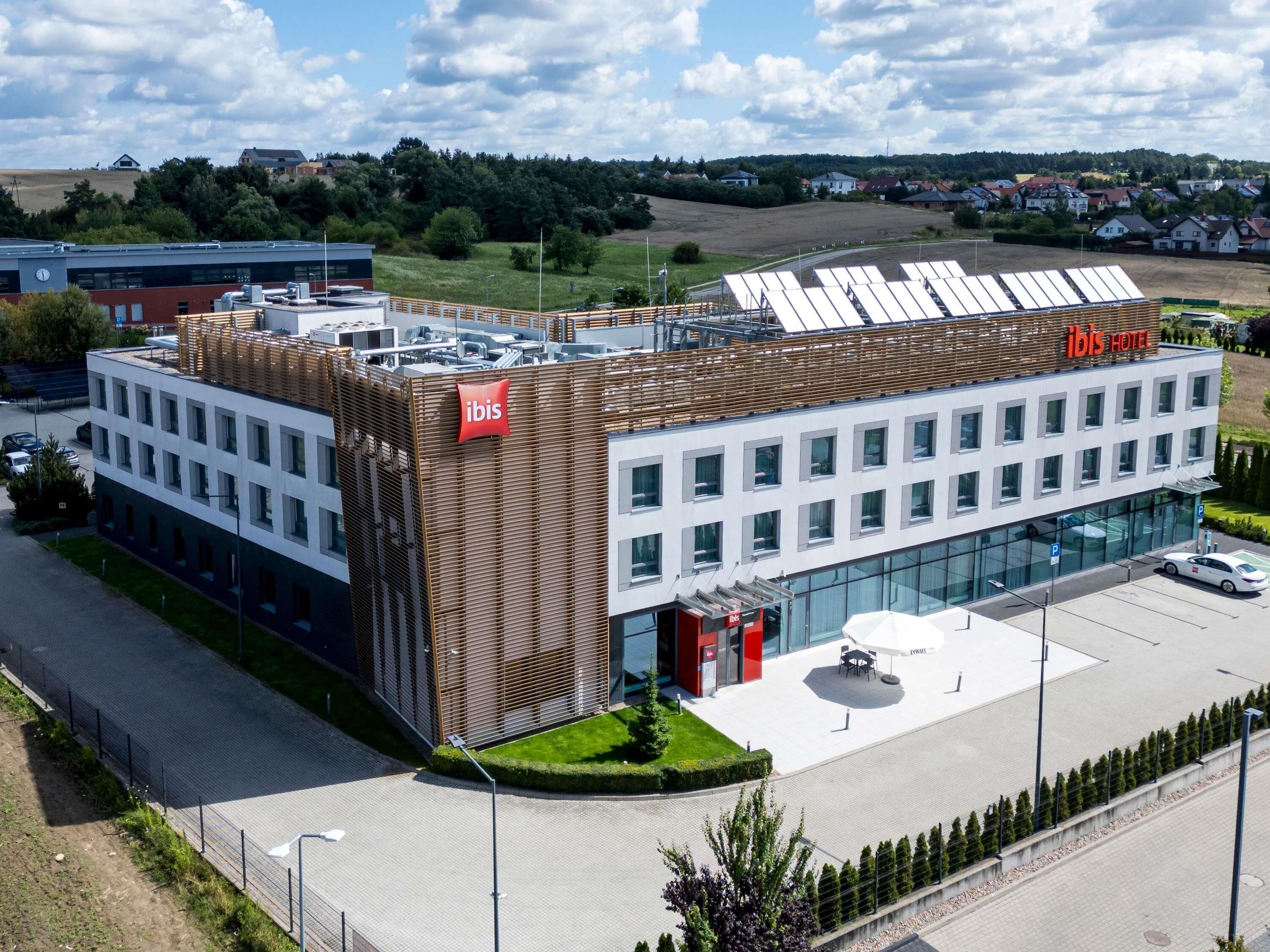 A modern hotel with a flat roof, a prominent 'ibis' logo, and a glass facade.