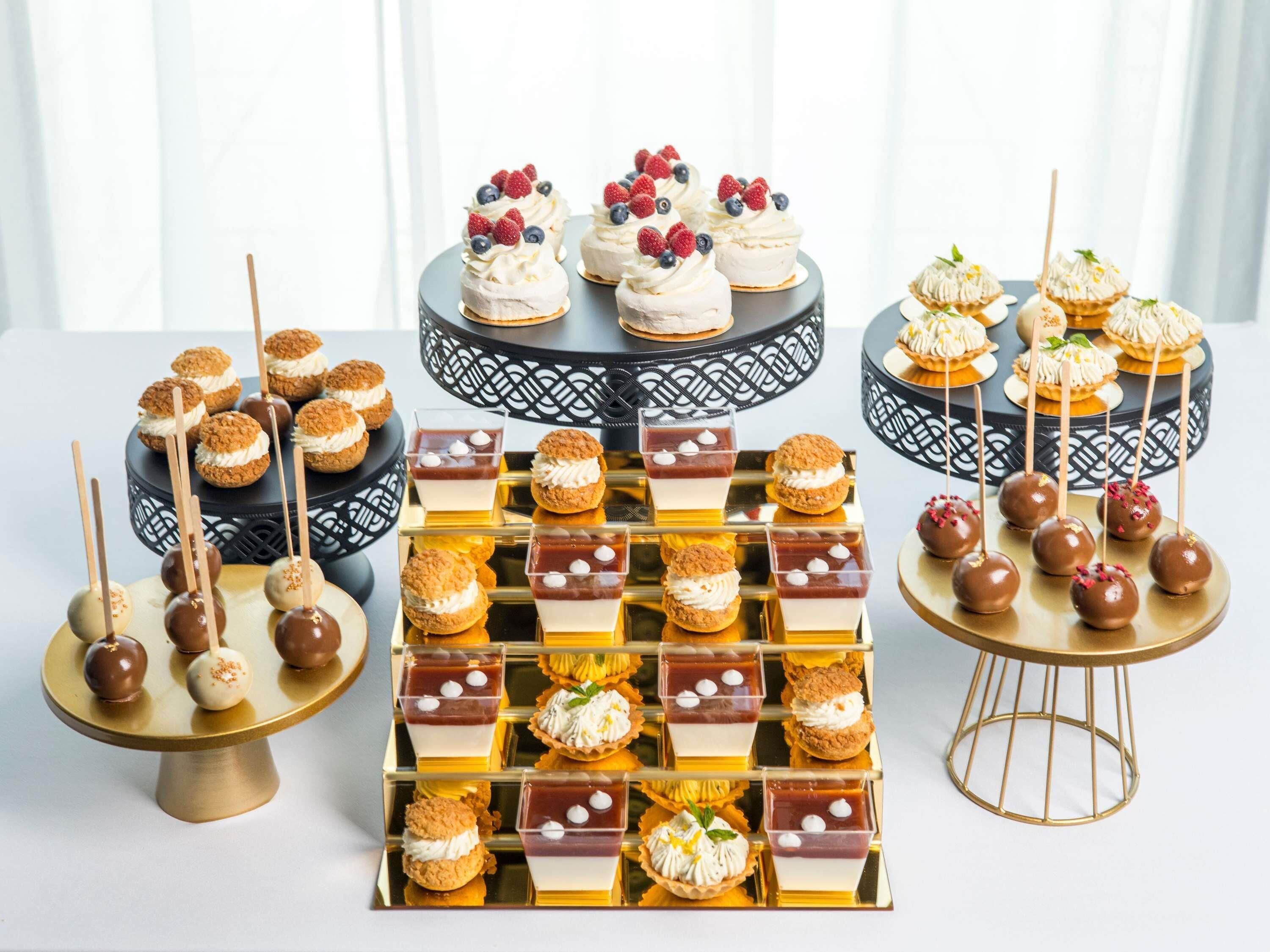 Diverse desserts gepresenteerd op etagères en een buffet.