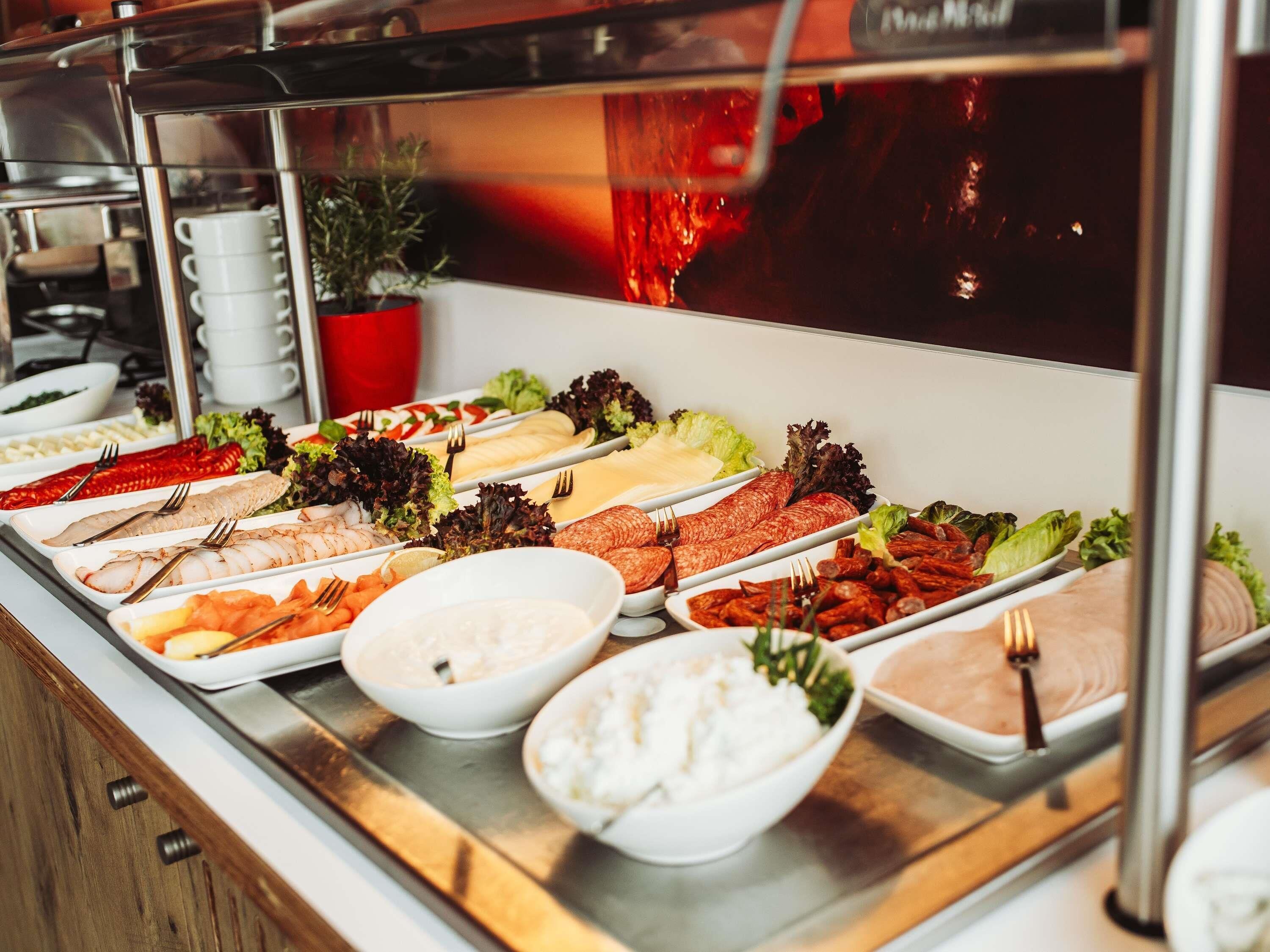 A buffet with various food options including meats, salads, and dips.