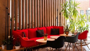 Un interior moderno con un sofá rojo, sillas negras y rojas, y una pared de listones de madera.