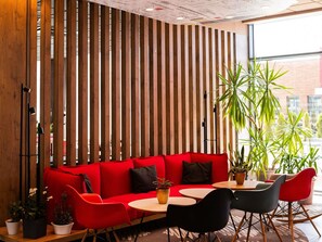 A modern interior with a red sofa, black and red chairs, and a wooden slatted wall.