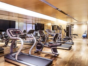 Un gimnasio con cintas de correr, elípticas y máquinas de pesas.