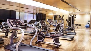 Une salle de sport équipée de tapis de course, de vélos elliptiques et d’appareils de musculation.