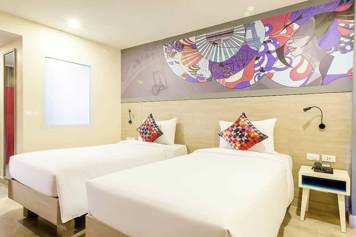 A hotel room with two beds, a nightstand, and a large abstract painting on the wall.