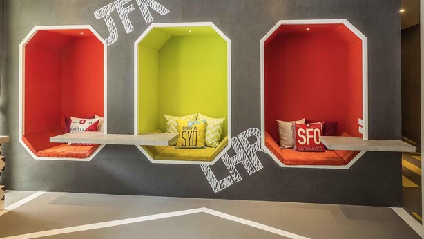Una pared con tres zonas de estar hexagonales, cada una de diferente color y con nombres de ciudades.