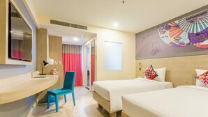 Habitación de hotel con dos camas, un escritorio, una silla y un ventanal grande.