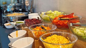 Un bufé con diversos alimentos, incluyendo frijoles, verduras y maíz.