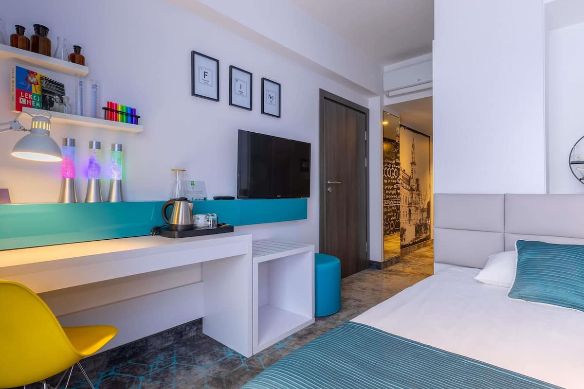 Una habitación de hotel moderna con cama, escritorio, televisor y minibar.