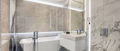 A modern bathroom with a freestanding bathtub, a vanity with a mirror, and a toilet.