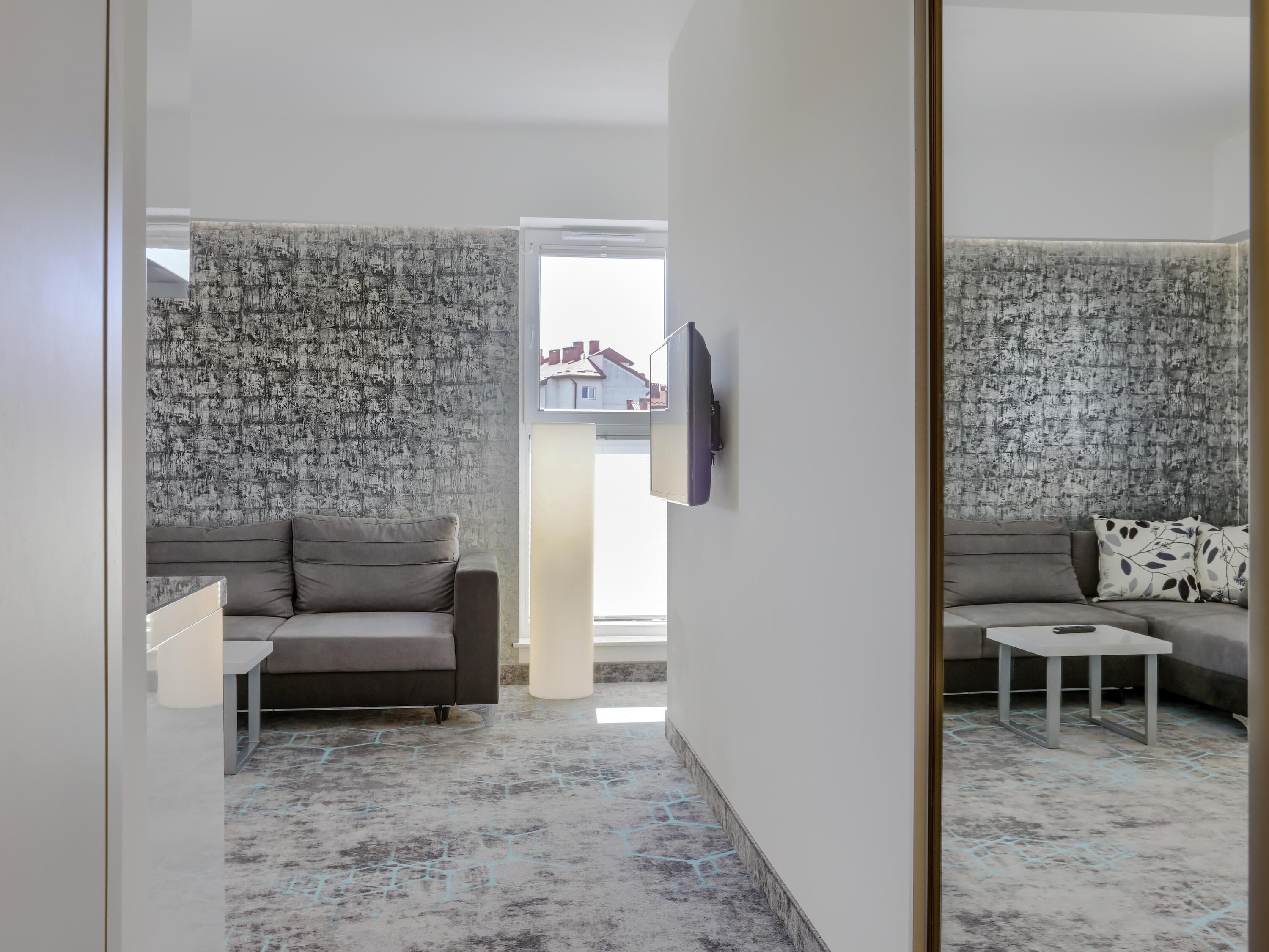 Una sala de estar moderna con dos sofás, una mesa de centro y un televisor montado en la pared.