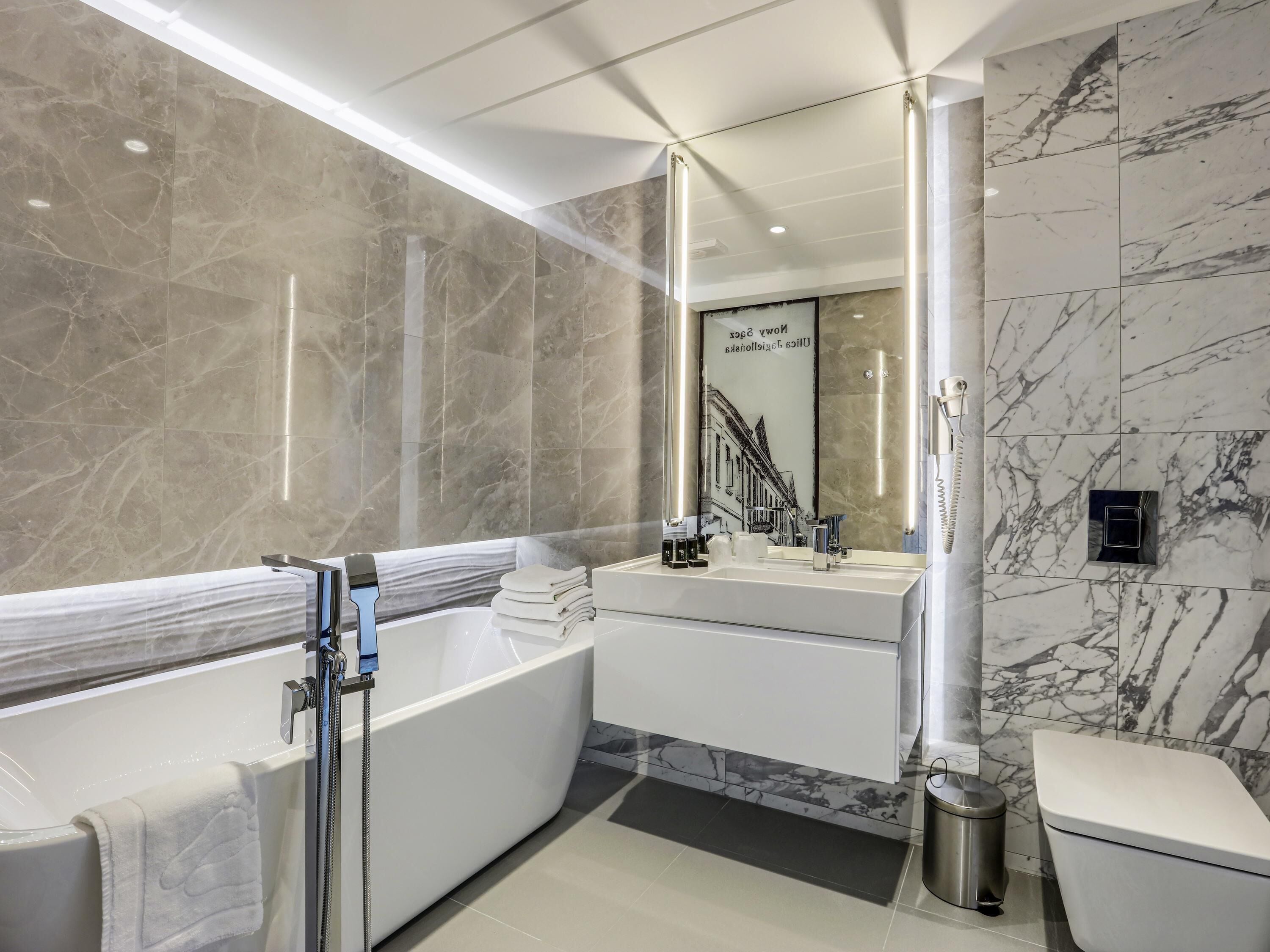 A modern bathroom with a freestanding bathtub, a vanity with a mirror, and a toilet.