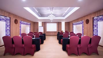 A conference room with red chairs and black tables, a chandelier, and patterned wall panels.