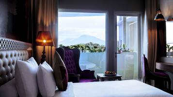 A hotel room with a bed, a lamp, a chair, and a view of the outdoors.