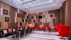 A modern conference room with a long table, red chairs, and a chandelier. - Grand Mercure Yogyakarta Adi Sucipto (Yogyakarta)