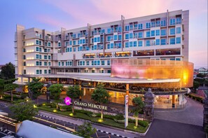 Un hôtel à plusieurs étages, doté d’un design moderne, avec une entrée imposante, une façade en verre et une enseigne indiquant « Grand Mercure ».