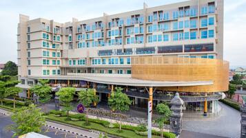 A multi-story hotel with a distinctive circular atrium and a well-maintained garden area.