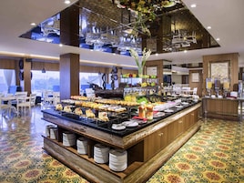 Un buffet proposant une variété de plats, une décoration sur le thème des navires et une vue sur la ville grâce à de grandes fenêtres.