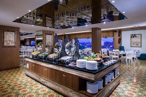 A buffet area with various food dishes, a seating area with tables and chairs, and a decorative ceiling with hanging lights. - Grand Mercure Yogyakarta Adi Sucipto (Yogyakarta)