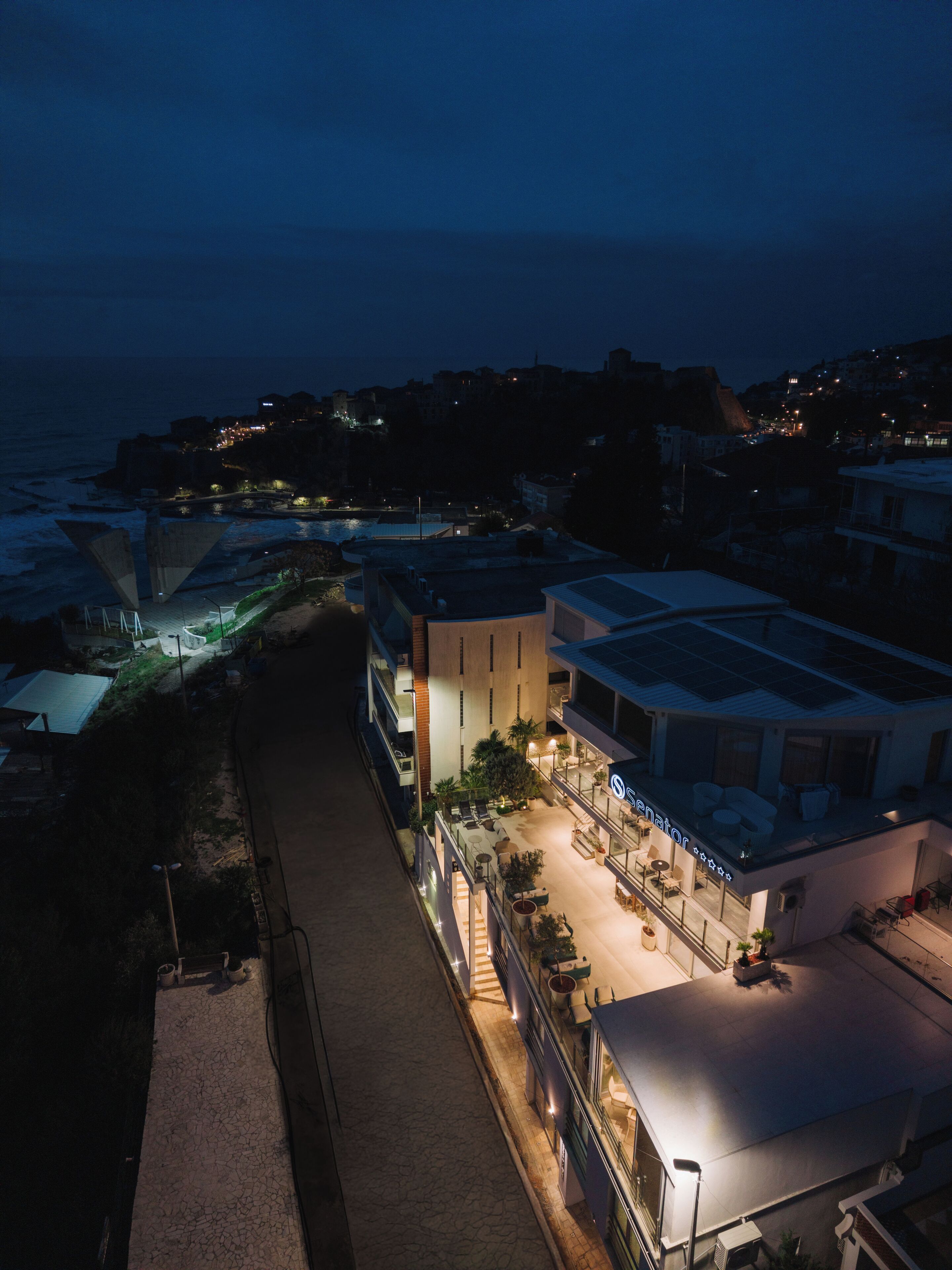 A hotel with a rooftop terrace, a pool, and a view of the sea.