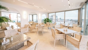 Un espacio interior amplio con diversas opciones de asientos, ventanas grandes y vistas a la ciudad.