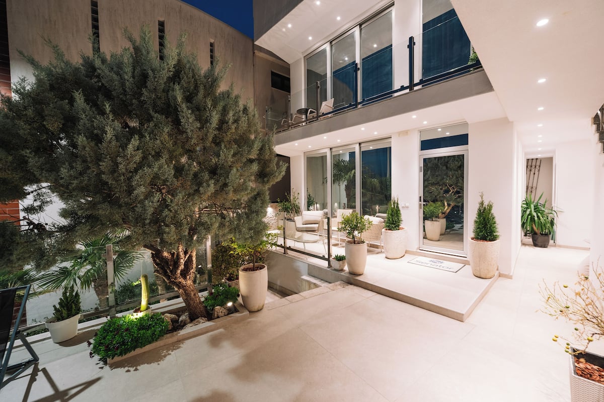 Una casa moderna con balcón, plantas en macetas y una entrada bien iluminada.