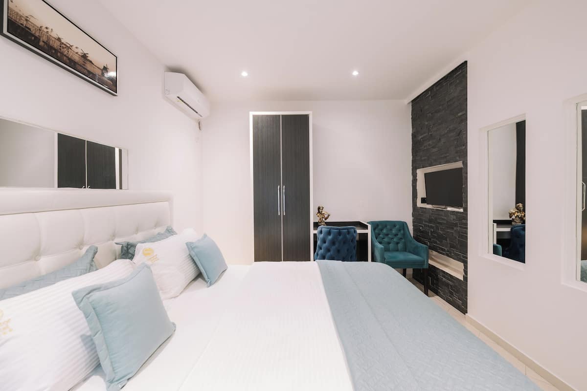 Un dormitorio moderno con una cama grande, un escritorio, una silla y un armario.