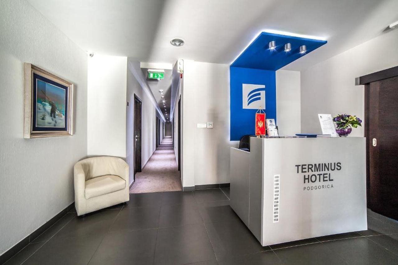 A reception desk with a blue accent, a framed picture on the wall, and a hallway leading to rooms.