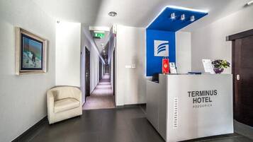 A reception desk with a blue accent, a framed picture on the wall, and a hallway leading to rooms.